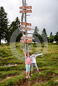 Children in frontÂ Wooden Signpost on Velika Planina in Slovenia